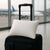 Almohada de viaje Dorminoite rectangular colocada sobre una maleta negra en un aeropuerto, con vista de aviones al fondo.